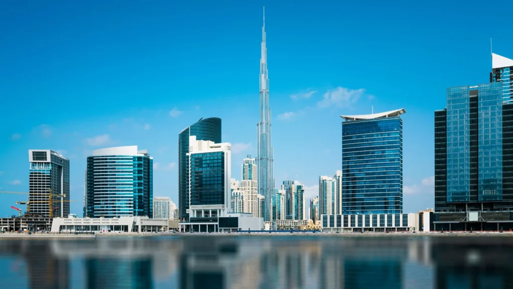 Business Bay canal daytime with Burj Khalifa centred and glass commercial towers — buying property in Dubai